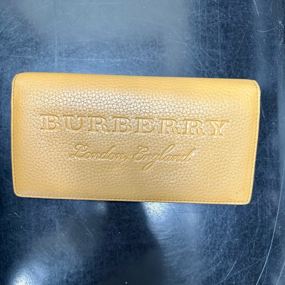 Burberrry “Embossed Leather Continental Wallet” in the color “ochre yellow”.